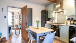 Une cuisine moderne avec un plancher en bois, une table à manger avec des chaises, un réfrigérateur et un lave-linge.