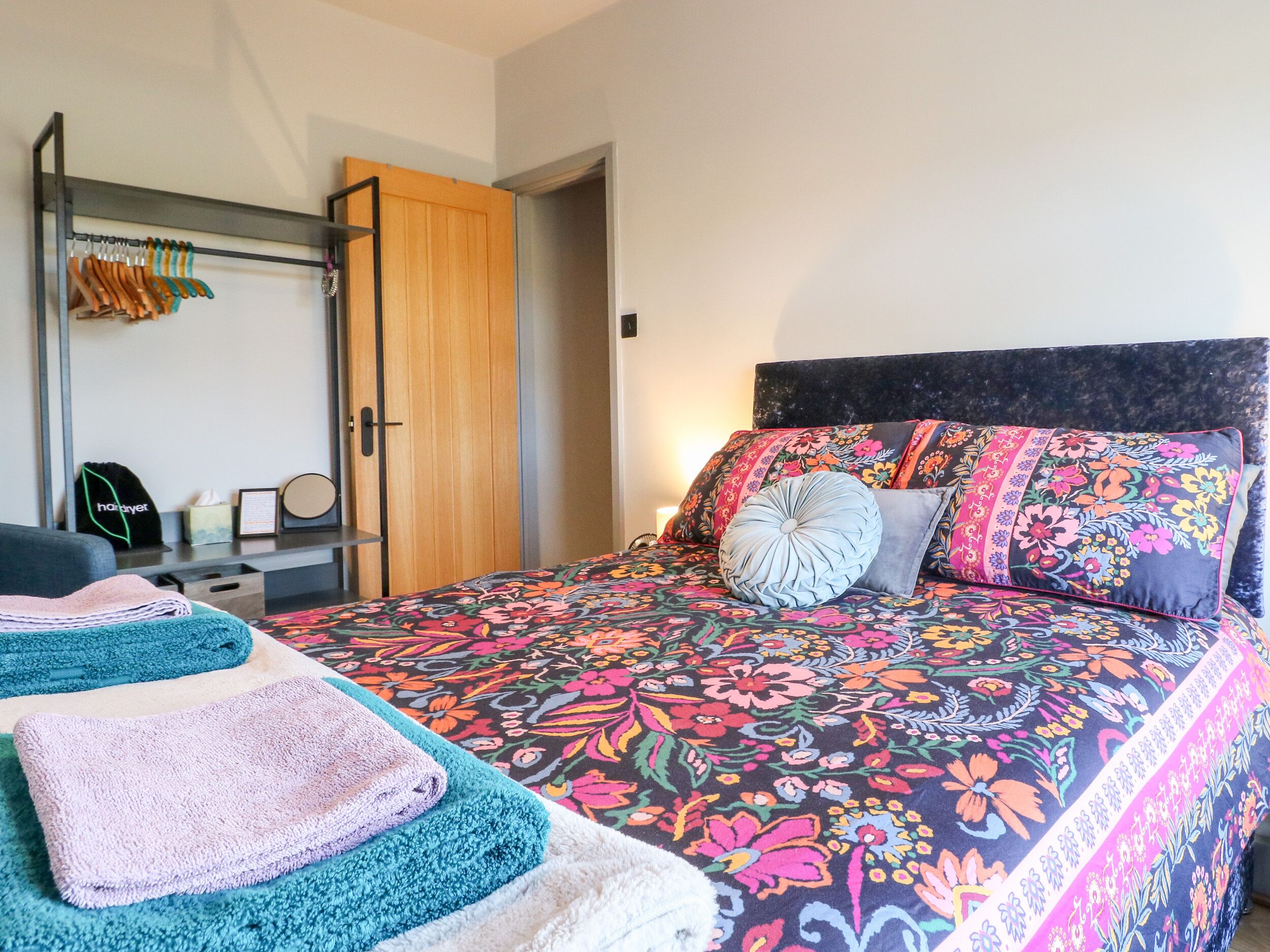 A bedroom with a bed, two towels, a wardrobe, and a bedside table.