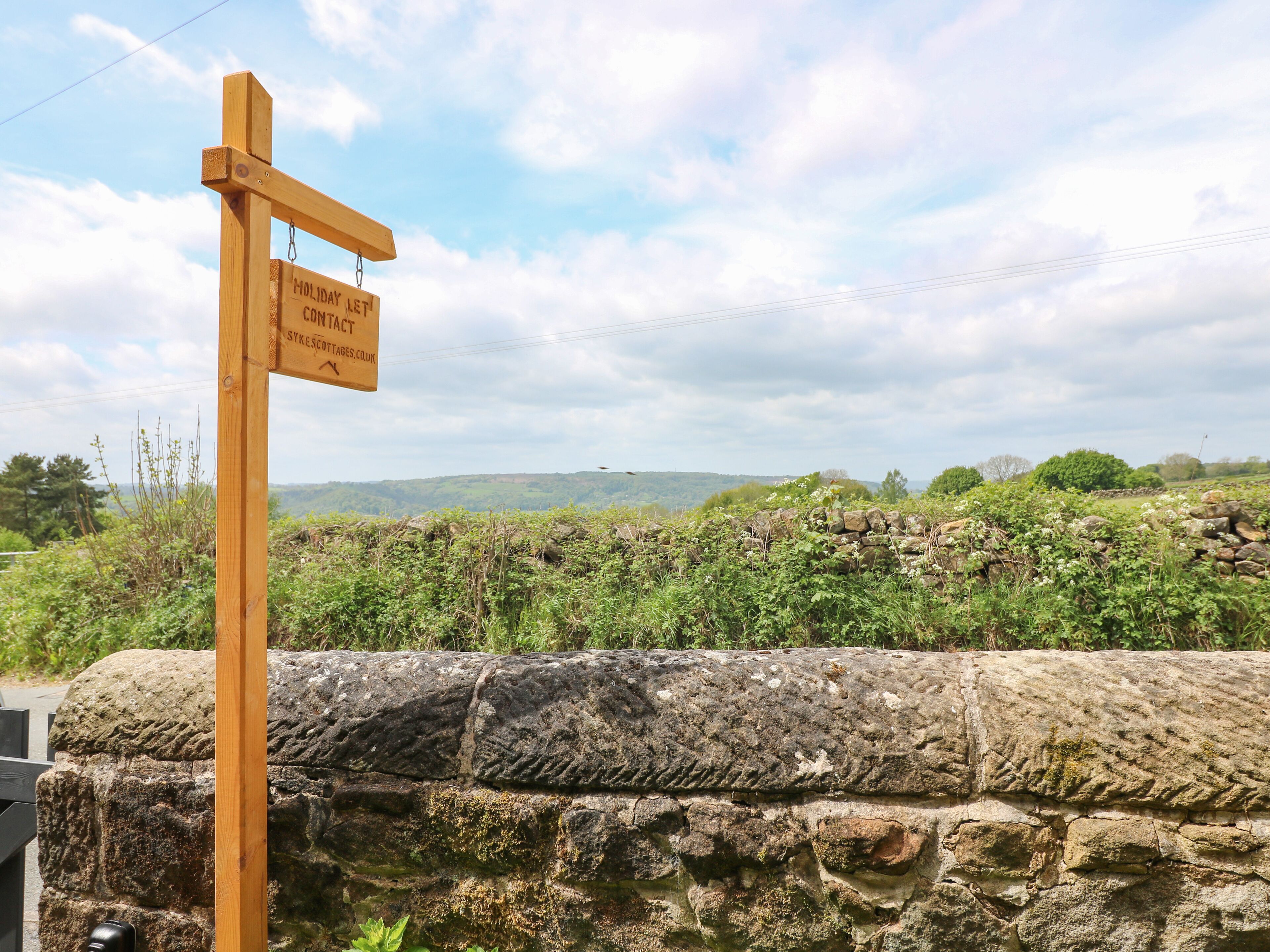A wooden signpost with contact information for Sykes Cottages.