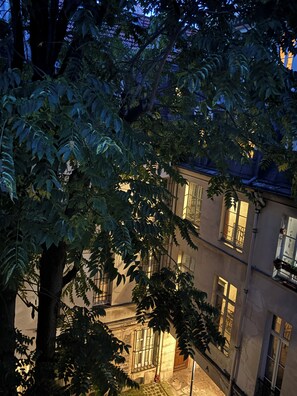 A multi-story building with balconies and windows, surrounded by dense foliage.