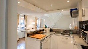 A modern kitchen with white cabinets, a wooden countertop, a sink, and a microwave.