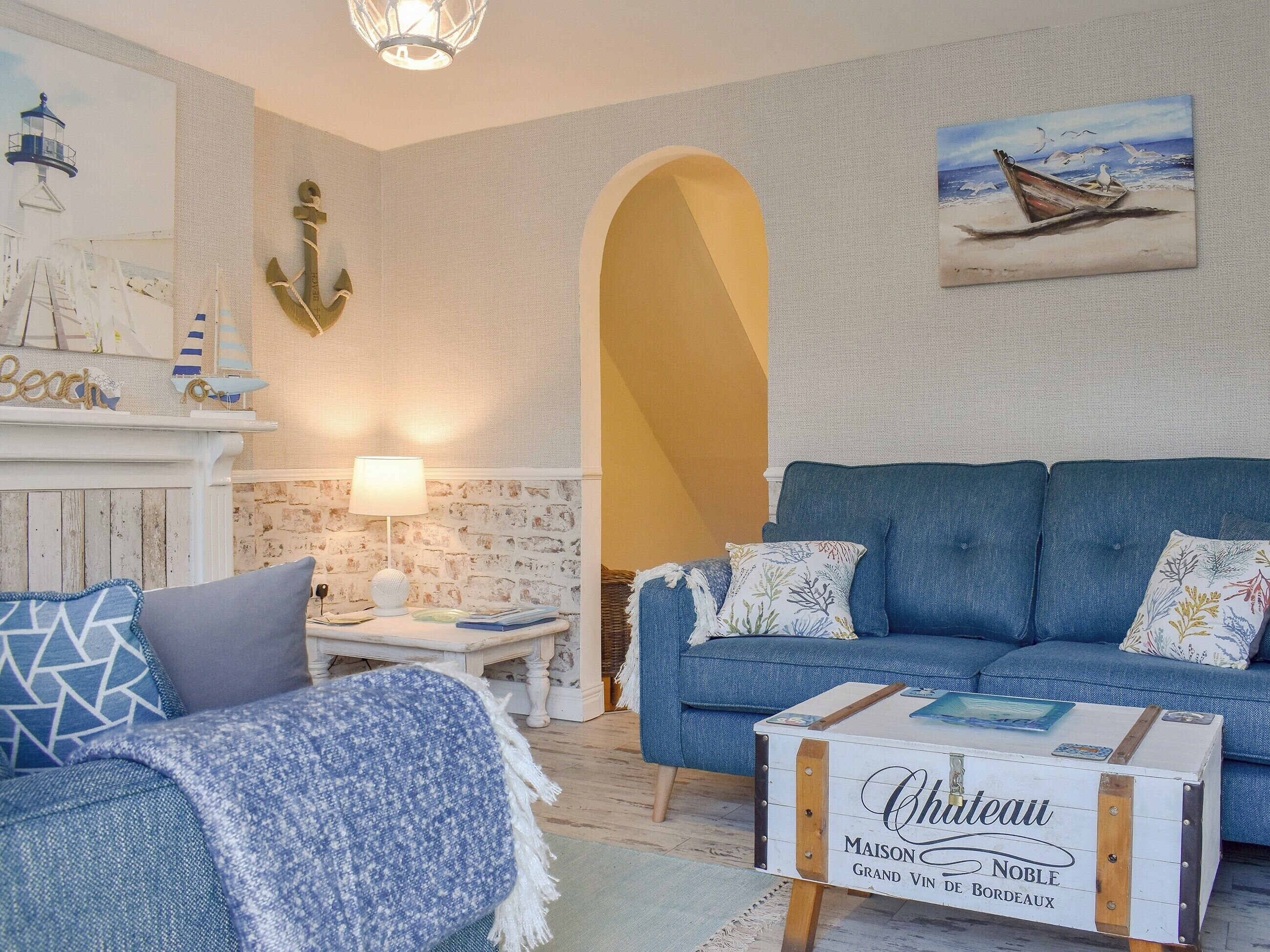 A living room with a blue sofa, a white coffee table, and a fireplace with nautical decor.