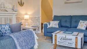 A living room with a blue sofa, a white coffee table, and a fireplace with nautical decor.