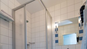 A bathroom with a glass-enclosed shower, a sink, a toilet, and a mirror. - Relaxed living in a centrally located apartment (Kleinblittersdorf)
