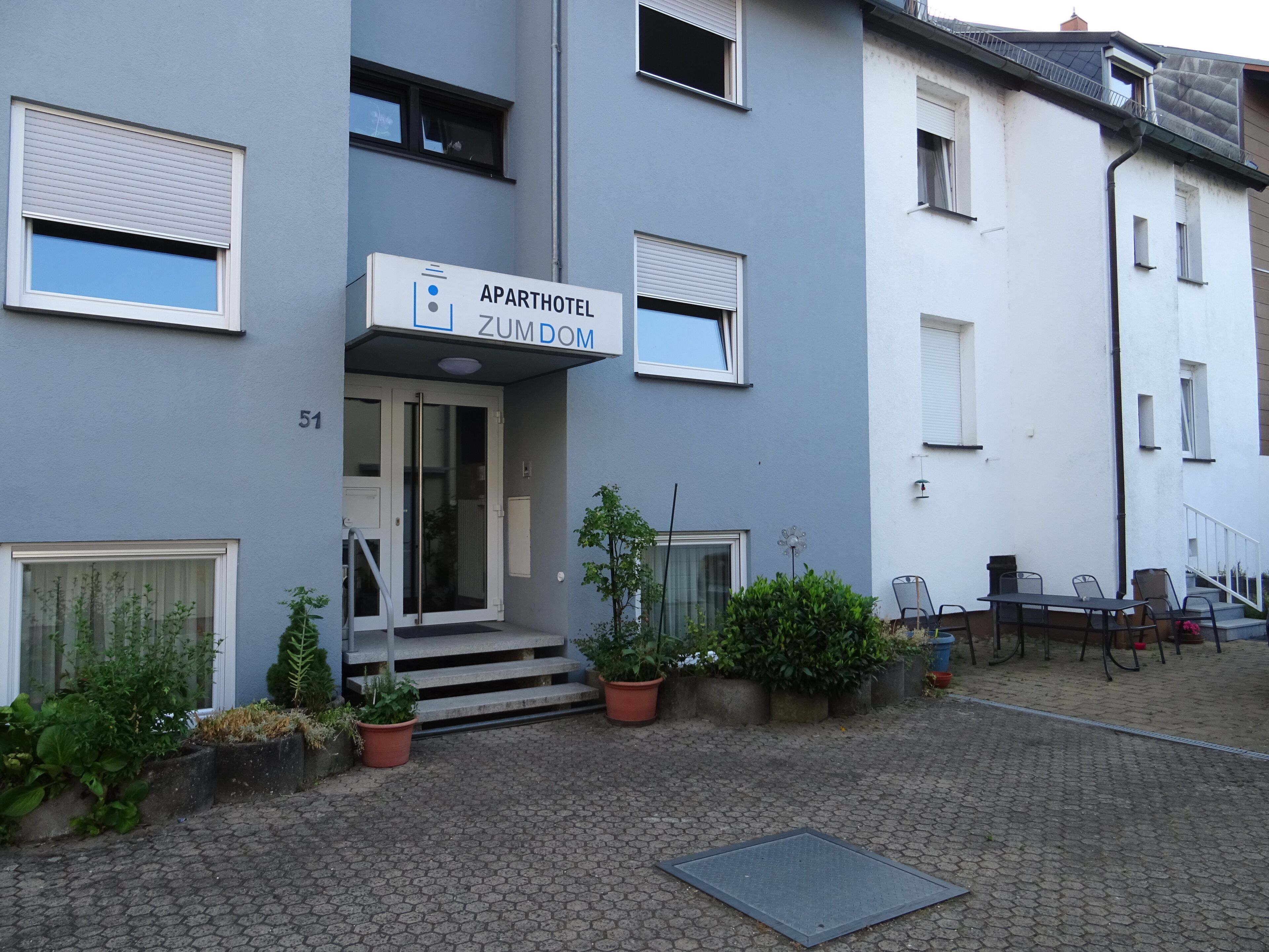 An apartment building with a sign reading "APARTHOTEL ZUMDOM" and a number "51" on the facade.