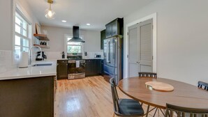 Een moderne keuken met een centraal eiland, inbouwapparatuur en een eethoek met een ronde tafel en stoelen.