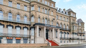 En historisk bygning med skiltning for Regency Mansions, der viser en imponerende indgang med trapper og en traditionel facade.