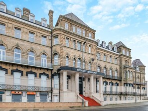 Ein historisches Gebäude mit der Beschilderung Regency Mansions, das einen prunkvollen Eingang mit Stufen und eine traditionelle Fassade zeigt.