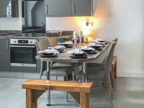 Eine moderne Küche mit Esstisch für sechs Personen, einem eingebauten Backofen und einer Bank davor.