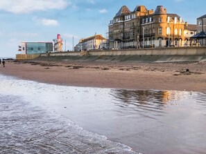 Een strand met een rij historische gebouwen op de achtergrond.