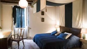 A bedroom with a bed, a chair, a desk, and a window with curtains. - Restored farmhouse, fenced garden 1.8 Ha, private swimming pool (Orthevielle)