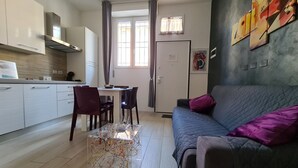 A modern living room with a grey sofa, purple cushions, and a dining area with a table and chairs. - Independent apartment in the heart of the city (Bologna)