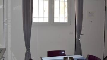 Een eethoek met een witte tafel, paarse stoelen, een schaal en een afstandsbediening.