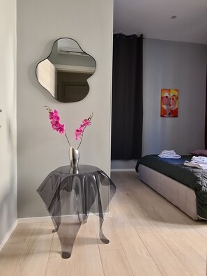 Un dormitorio moderno con una cama, una mesita con un florero y un equipo de aire acondicionado instalado en la pared.