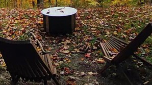 Pyöreä pöytä ja tuolit metsäisellä alueella, jossa maassa on pudonneita lehtiä.