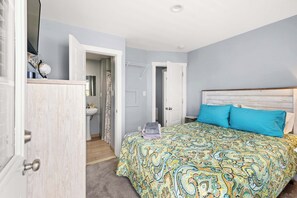 Ein Schlafzimmer mit Bett, Kleiderschrank, Bad und einer Tür zu einem weiteren Raum.