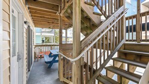 Eine Holztreppe mit Geländer, ein Holzboden und ein Blick auf ein Gebäude im Hintergrund.