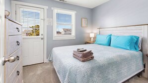 A bedroom with a bed, a dresser, two windows, and a door. - Midtown Beach Escape - Ocean Block | Parking | 3W (Ocean City)