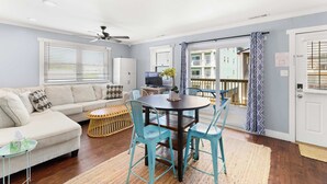 A living room with a sofa, a dining table with chairs, a ceiling fan, and a view of a balcony. - Midtown Beach Escape - Ocean Block | Parking | 3W (Ocean City)