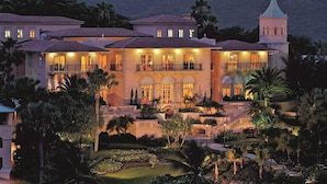 A large, multi-story building with a prominent tower, surrounded by lush landscaping and palm trees. - Ritz-Carlton Club® / 2 Bed Lux Suite* (Fri to Fri) (St Thomas)