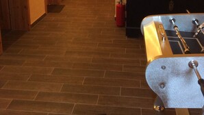 Un couloir avec un plancher en bois, un lit avec une tête de lit et un extincteur rouge.
