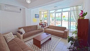 Ein geräumiges Wohnzimmer mit zwei Sofas, einem Couchtisch und einem großen Fenster mit Blick auf einen Pool und einen Außenbereich.