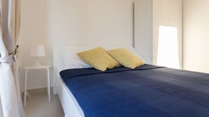 A bedroom with a bed, a white wardrobe, and a small white table with a lamp. - Fig&Olive Apartments 2 (Zaton)