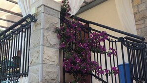 A stone building with a balcony, white curtains, and purple flowers. - Fig&Olive Apartments 2 (Zaton)