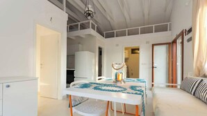 A modern, well-lit room with a dining table, chairs, and a bed. - Fig&Olive Apartments 2 (Zaton)