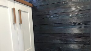 Une cuisine avec des meubles blancs et un mur d’accent en bois noir.