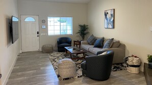 Ein geräumiges Wohnzimmer mit Deckenventilator, einer Couch, einem Couchtisch und einem gemusterten Teppich.