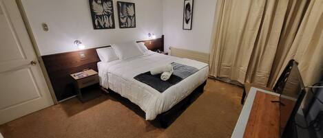 A hotel room with a bed, a nightstand, a lamp, and artwork on the wall.