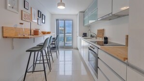 A modern kitchen with a wooden countertop, bar stools, and a large window. - A-MO Sesimbra by Trip2Portugal (Sesimbra)