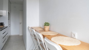 Een moderne keuken met witte kasten, een houten aanrechtblad en een kleine potplant.