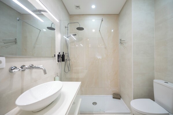 Une salle de bain moderne avec une douche à parois de verre, un lavabo blanc et des toilettes.