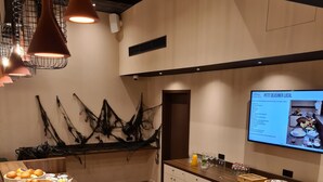 A modern hotel dining area with a buffet setup, including various food items and a digital menu display. - Pegard Andenne Centre (Andenne)