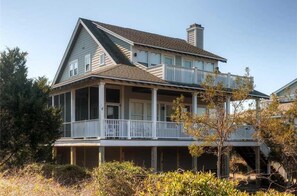 A two-story house with a balcony on the upper floor, a covered porch on the ground floor, and a chimney on the roof.