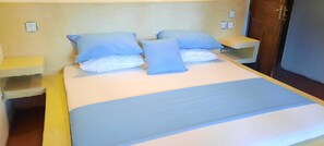 Een bed met blauw beddengoed, twee nachtkastjes en een houten deur op de achtergrond.
