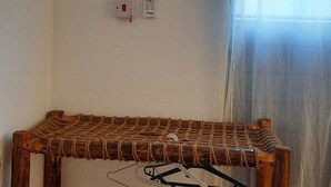 Een kamer met een houten schapkas, een airconditioning, een stopcontact en een raam met gordijn.