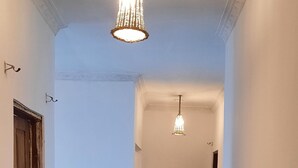 Een hal met glanzende zwarte betegelde vloer, witte muren en twee hangende lampen.
