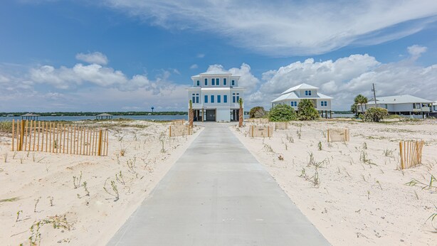 Une propriété située en bord de mer, comprenant un bâtiment principal, une dépendance et un chemin de sable menant à l’entrée.