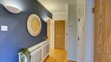 A hallway with a dark blue wall, a decorative mirror, and a wooden door.