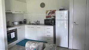 Une cuisine de taille réduite avec des meubles blancs, un four à micro-ondes, un grille-pain et un réfrigérateur.