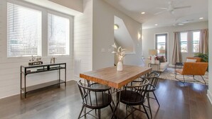 A modern living room with a wooden dining table, black chairs, a glass coffee table, and a sofa. - Modern Luxe Escape | Rooftop Views | Near Downtown (Nashville)