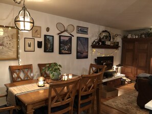 A cozy dining area with wooden furniture, a chandelier, and wall-mounted artwork. - Walk to Fort Worden (Port Townsend)