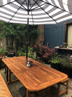 A wooden patio table with a striped umbrella overhead. - Walk to Fort Worden (Port Townsend)