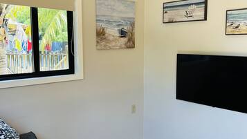 Una sala de estar con un sofá, un ventilador de techo, un televisor y obras de arte en las paredes.