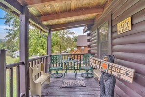 A wooden cabin porch with a bench, two chairs, a small table, and a welcome mat. - Bear Claw Cove #2 Pet Friendly-Hot tub-Kayak  (Pipestem)