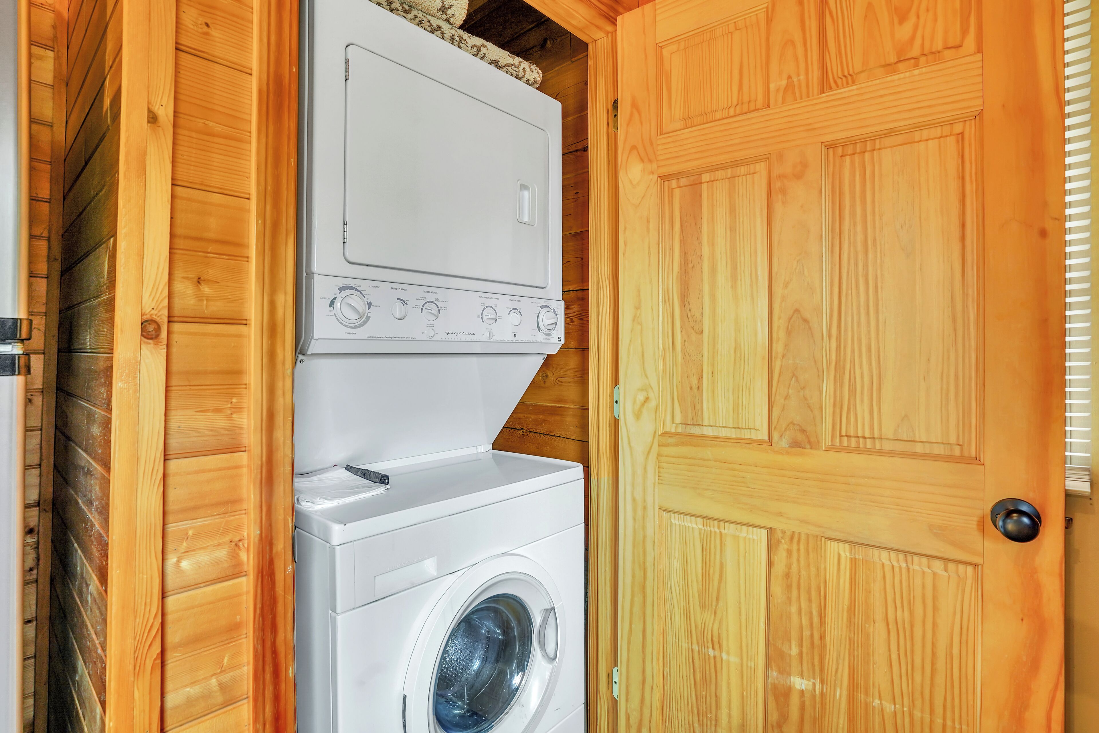 Une buanderie équipée d’un lave-linge et d’un sèche-linge, avec des murs en bois et une porte.