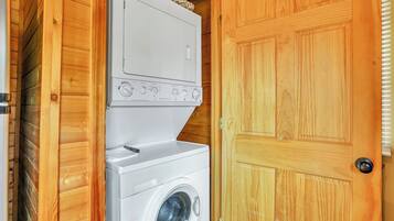 Une buanderie équipée d’un lave-linge et d’un sèche-linge, avec des murs en bois et une porte.